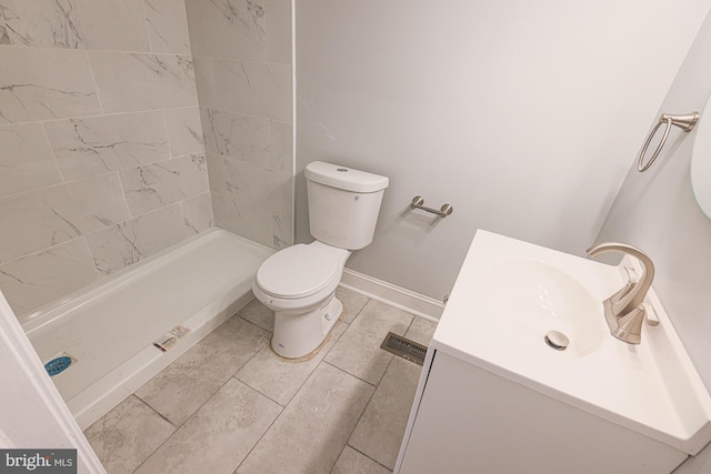 bathroom featuring tiled shower, vanity, and toilet