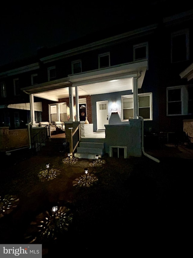 back house at night featuring a porch