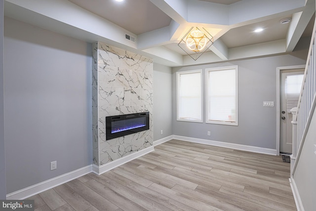 unfurnished living room with a premium fireplace, plenty of natural light, and light wood-type flooring