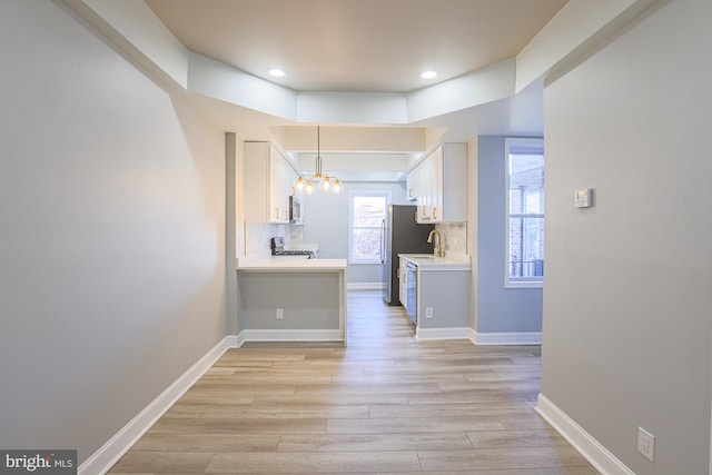 corridor with light wood-type flooring, a notable chandelier, and sink