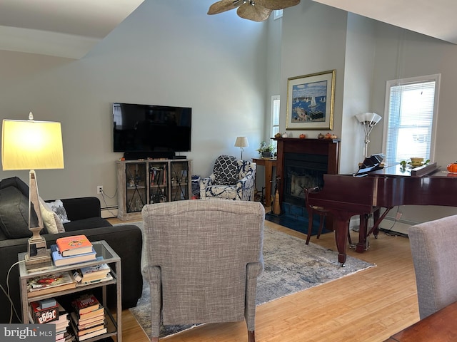 living room featuring ceiling fan, wood-type flooring, a baseboard radiator, and high vaulted ceiling