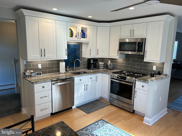 kitchen featuring light wood-type flooring, appliances with stainless steel finishes, decorative backsplash, sink, and white cabinets