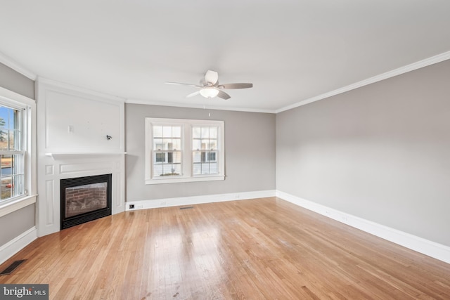 unfurnished living room featuring plenty of natural light, ornamental molding, and ceiling fan