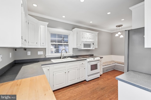 kitchen with sink, hanging light fixtures, light hardwood / wood-style floors, white appliances, and white cabinets