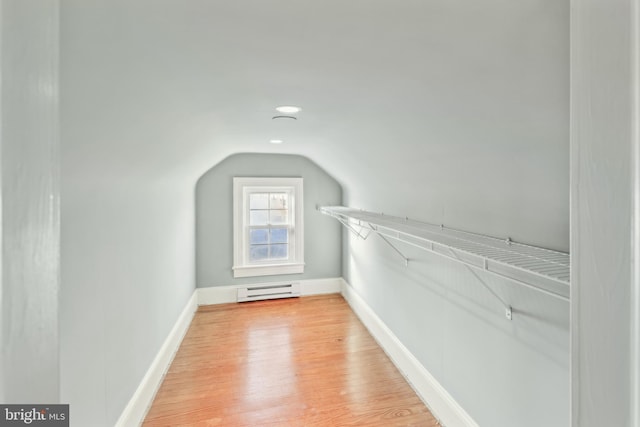 additional living space featuring baseboard heating, wood-type flooring, and vaulted ceiling