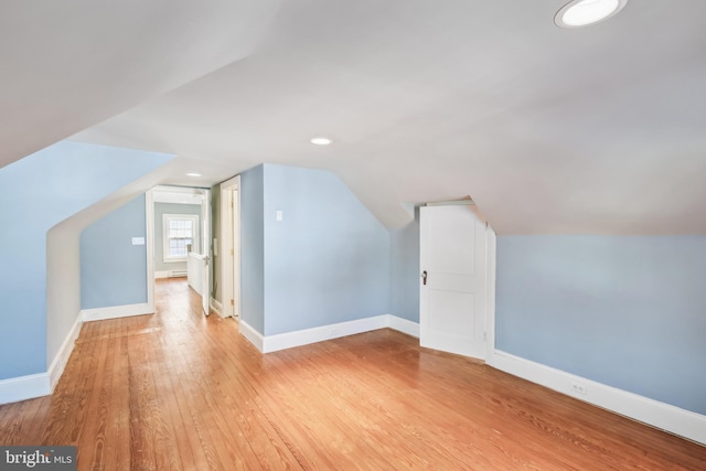 additional living space with light wood-type flooring and vaulted ceiling