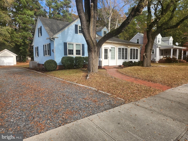 new england style home featuring a garage, central AC unit, and an outdoor structure