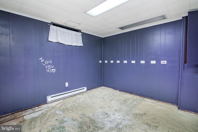 empty room featuring baseboard heating and wood walls