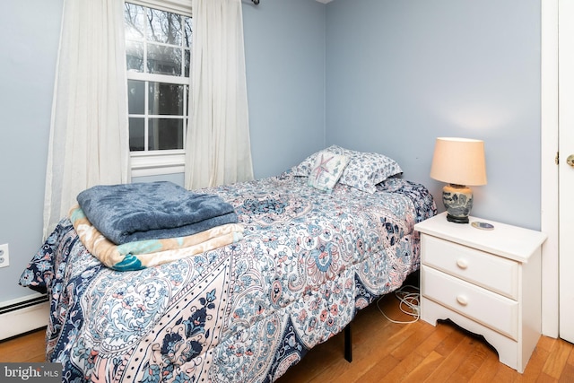 bedroom featuring hardwood / wood-style flooring and a baseboard heating unit