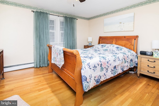 bedroom with light hardwood / wood-style flooring, baseboard heating, and ceiling fan