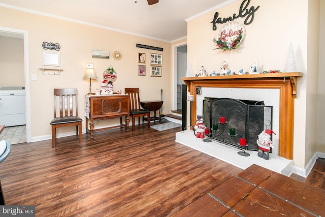 living room featuring crown molding, ceiling fan, dark hardwood / wood-style floors, a fireplace, and washer / clothes dryer