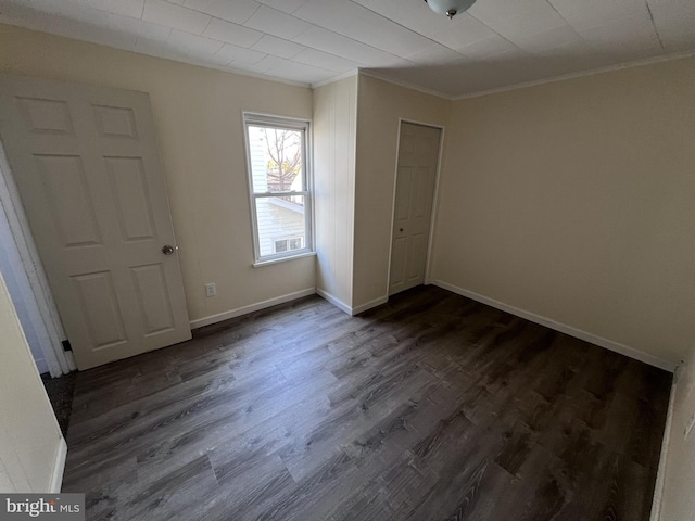 unfurnished bedroom featuring crown molding, dark wood-type flooring, and a closet