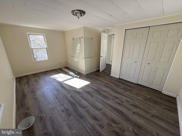 unfurnished bedroom with dark hardwood / wood-style floors, crown molding, and a closet