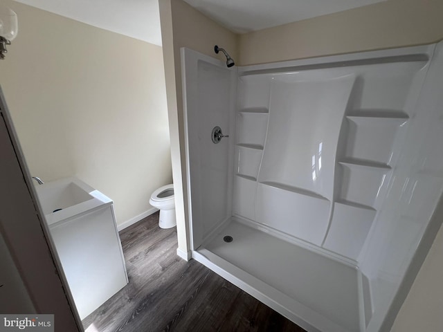 bathroom with hardwood / wood-style floors, toilet, a shower, and sink