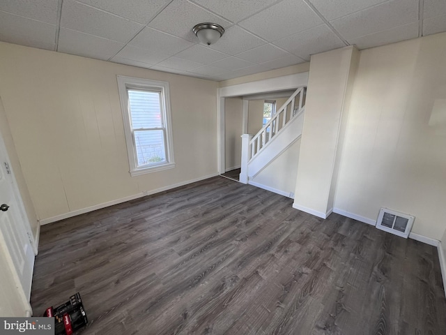 empty room featuring a paneled ceiling and dark wood-type flooring