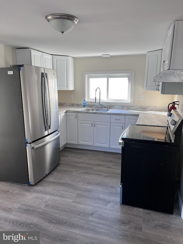 kitchen with range with electric cooktop, sink, stainless steel fridge, light hardwood / wood-style floors, and white cabinets