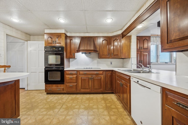 kitchen featuring premium range hood, a paneled ceiling, sink, and black appliances