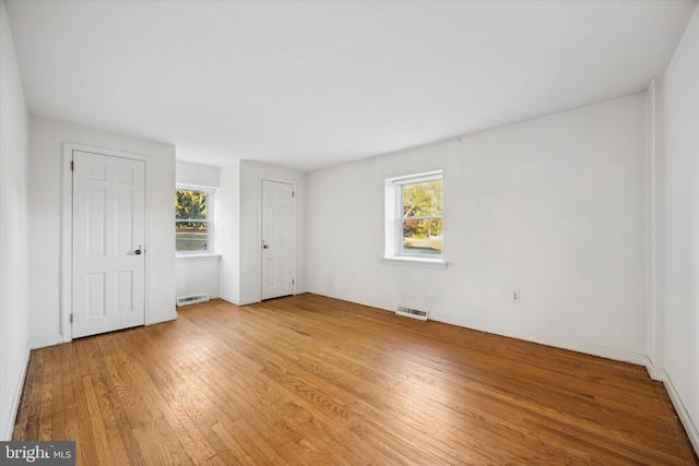 unfurnished bedroom with multiple windows and light hardwood / wood-style floors