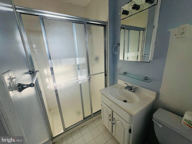 bathroom featuring tile patterned floors, vanity, a shower with shower door, and toilet