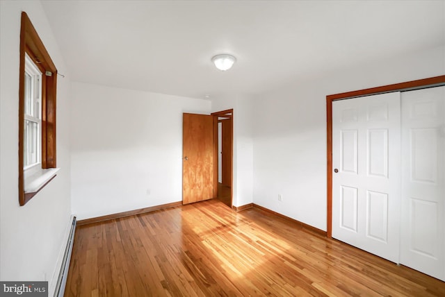 3315 E College Ave, Bellefonte, PA 16823 - unfurnished bedroom with a baseboard radiator, light wood-style floors, baseboards, and a closet