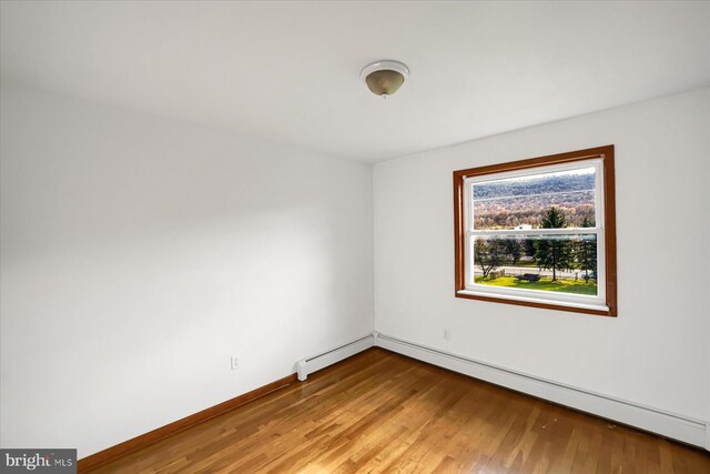 spare room with a baseboard radiator and light hardwood / wood-style flooring