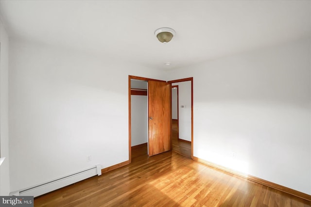 unfurnished bedroom featuring a baseboard heating unit and light hardwood / wood-style flooring