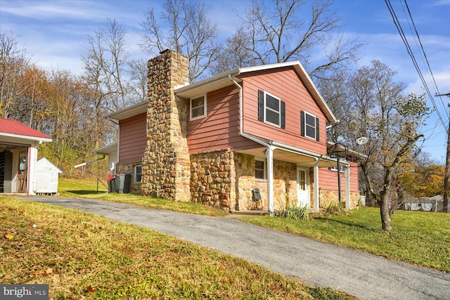 3315 E College Ave, Bellefonte, PA 16823 - view of front facade with stone siding, a chimney, a front yard, covered porch, and asphalt driveway