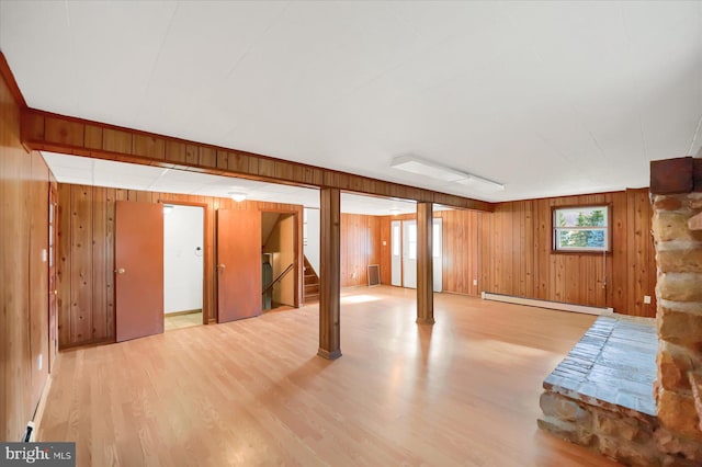 basement featuring baseboard heating, wooden walls, and light hardwood / wood-style flooring