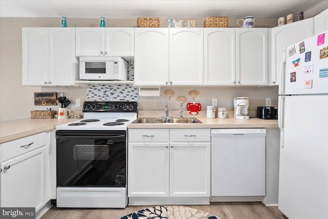 kitchen with decorative backsplash, sink, white cabinetry, light wood-type flooring, and white appliances