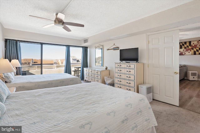 carpeted bedroom featuring ceiling fan and a textured ceiling