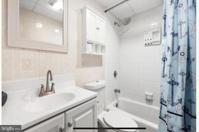 full bathroom with tile walls, vanity, shower / bath combination with curtain, and tasteful backsplash