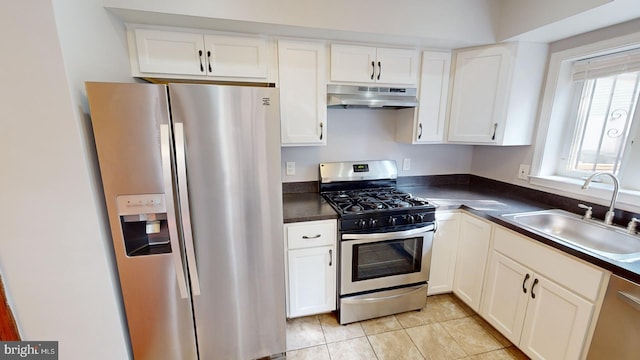 kitchen featuring appliances with stainless steel finishes, sink, light tile patterned floors, and white cabinets