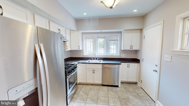 kitchen featuring appliances with stainless steel finishes, sink, light tile patterned floors, and white cabinets