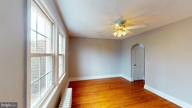 spare room featuring a wealth of natural light, radiator heating unit, hardwood / wood-style floors, and ceiling fan