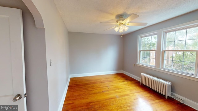 empty room featuring radiator, a textured ceiling, ceiling fan, and light hardwood / wood-style flooring