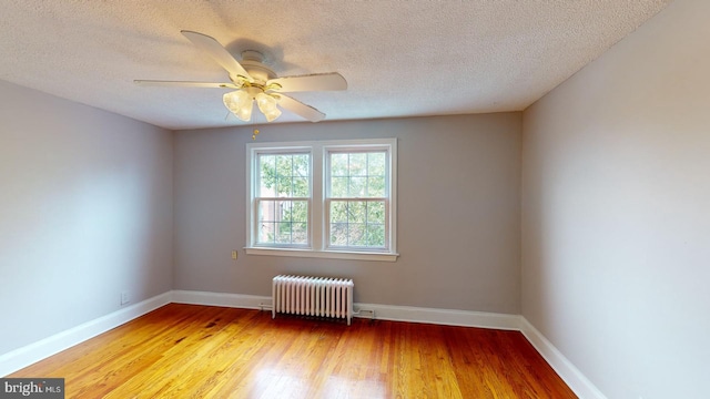 empty room with wood-type flooring, a textured ceiling, ceiling fan, and radiator