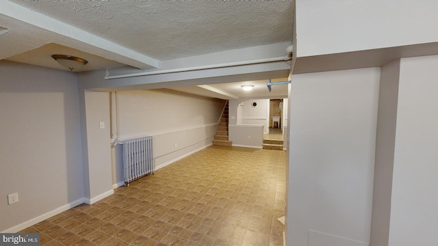 basement featuring radiator heating unit and a textured ceiling