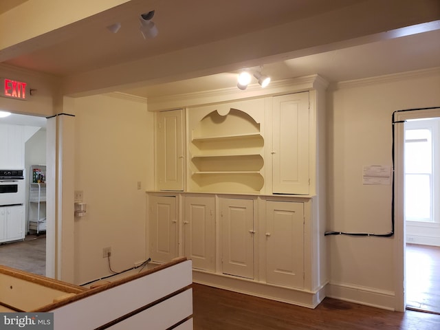 kitchen featuring dark hardwood / wood-style flooring, oven, ornamental molding, and white cabinets