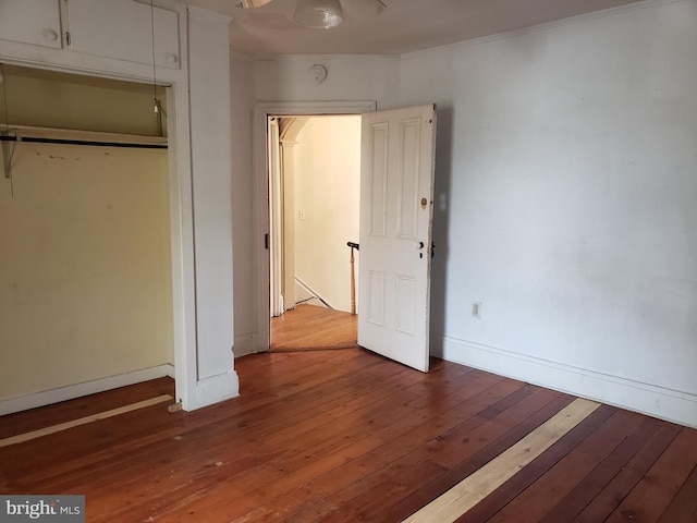 unfurnished bedroom featuring hardwood / wood-style flooring, crown molding, and a closet