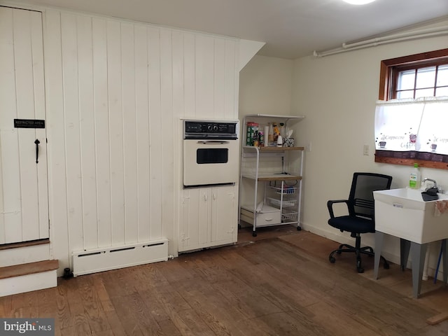 home office with dark hardwood / wood-style flooring and a baseboard radiator