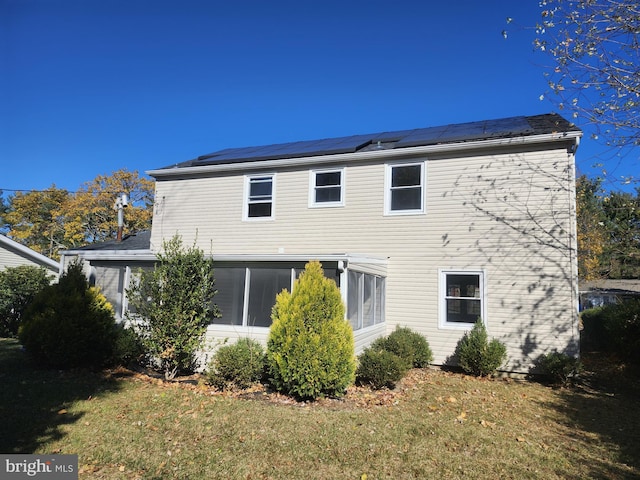 back of property featuring solar panels and a lawn