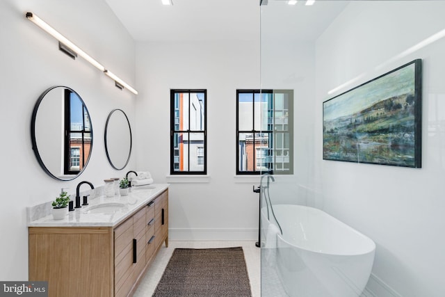 bathroom with a tub to relax in, vanity, and tile patterned flooring