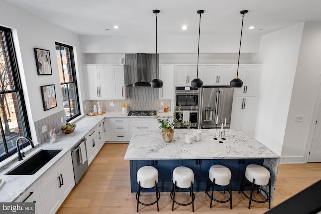 kitchen with stainless steel appliances, wall chimney range hood, a healthy amount of sunlight, and a center island