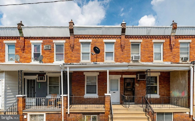 townhome / multi-family property with an AC wall unit, a porch, and cooling unit