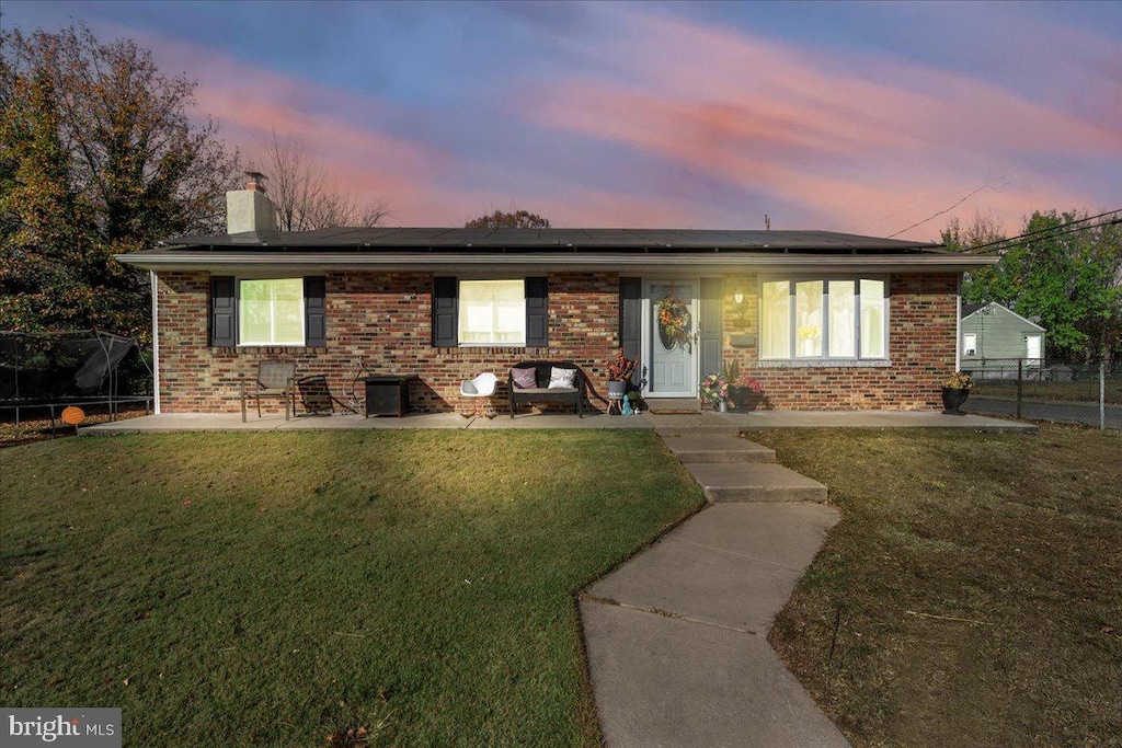 single story home with a lawn, solar panels, and a patio area