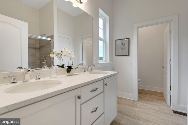 bathroom featuring vanity, an enclosed shower, and toilet