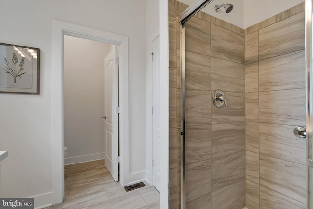 bathroom with toilet and a shower with door