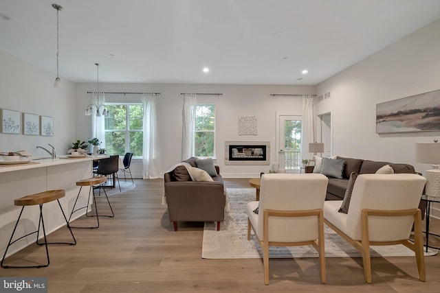 living room with an inviting chandelier, light hardwood / wood-style flooring, and sink