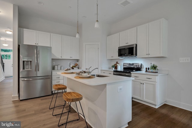 kitchen featuring stainless steel appliances, sink, hardwood / wood-style flooring, white cabinetry, and an island with sink