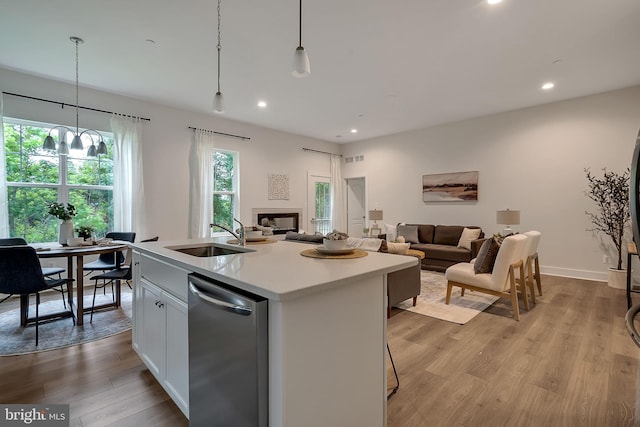 kitchen with white cabinetry, sink, pendant lighting, a kitchen island with sink, and dishwasher